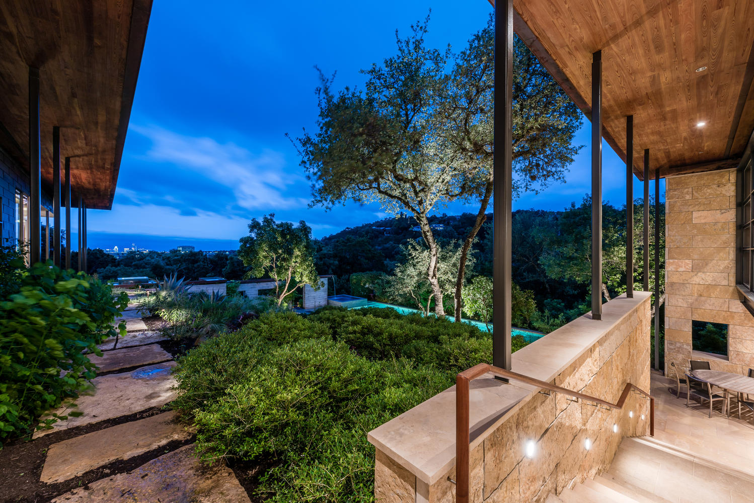 The pool and covered porch at dusk, framed by an oak tree
