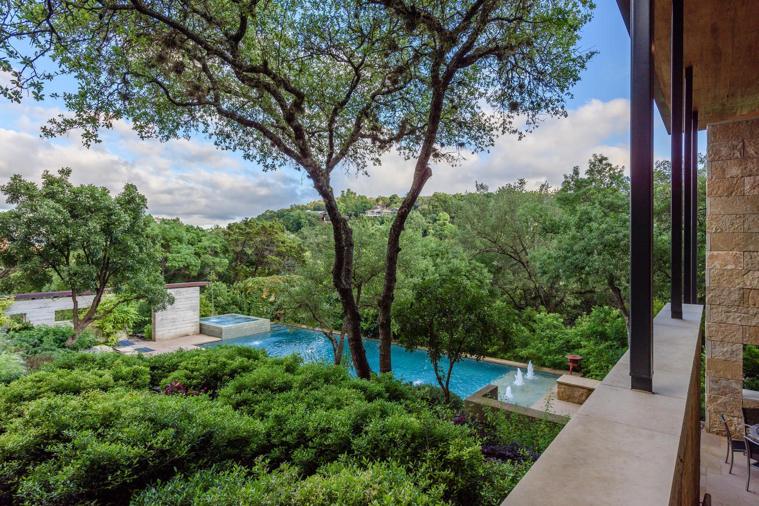 The infinity pool and hot tub framed by trees, overlooking the wooded hillside